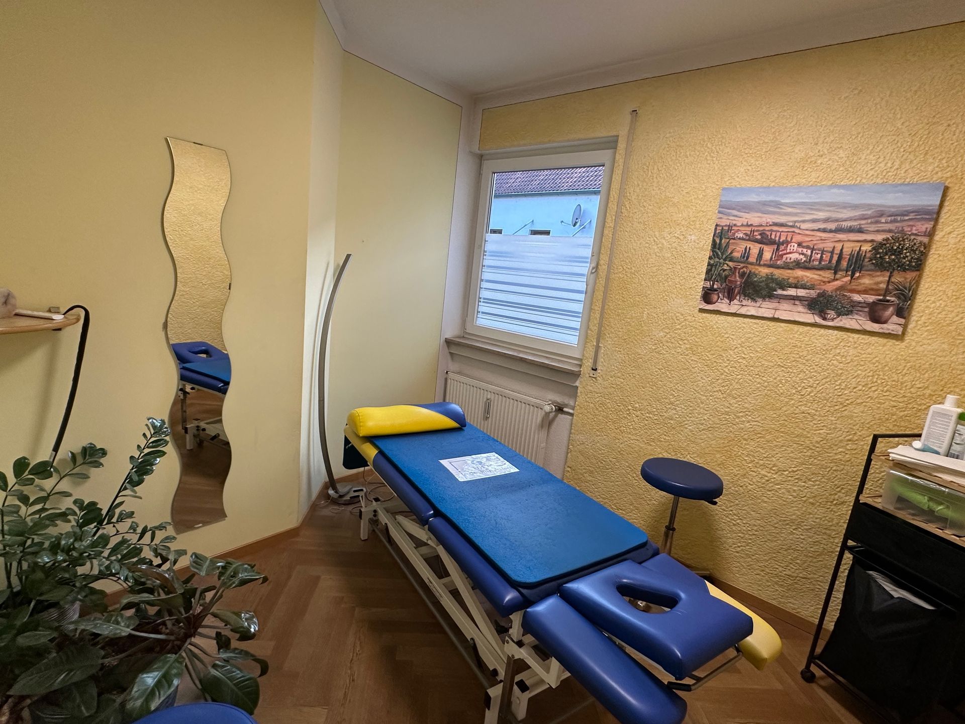 Behandlungsraum mit Therapieliege und Spiegel