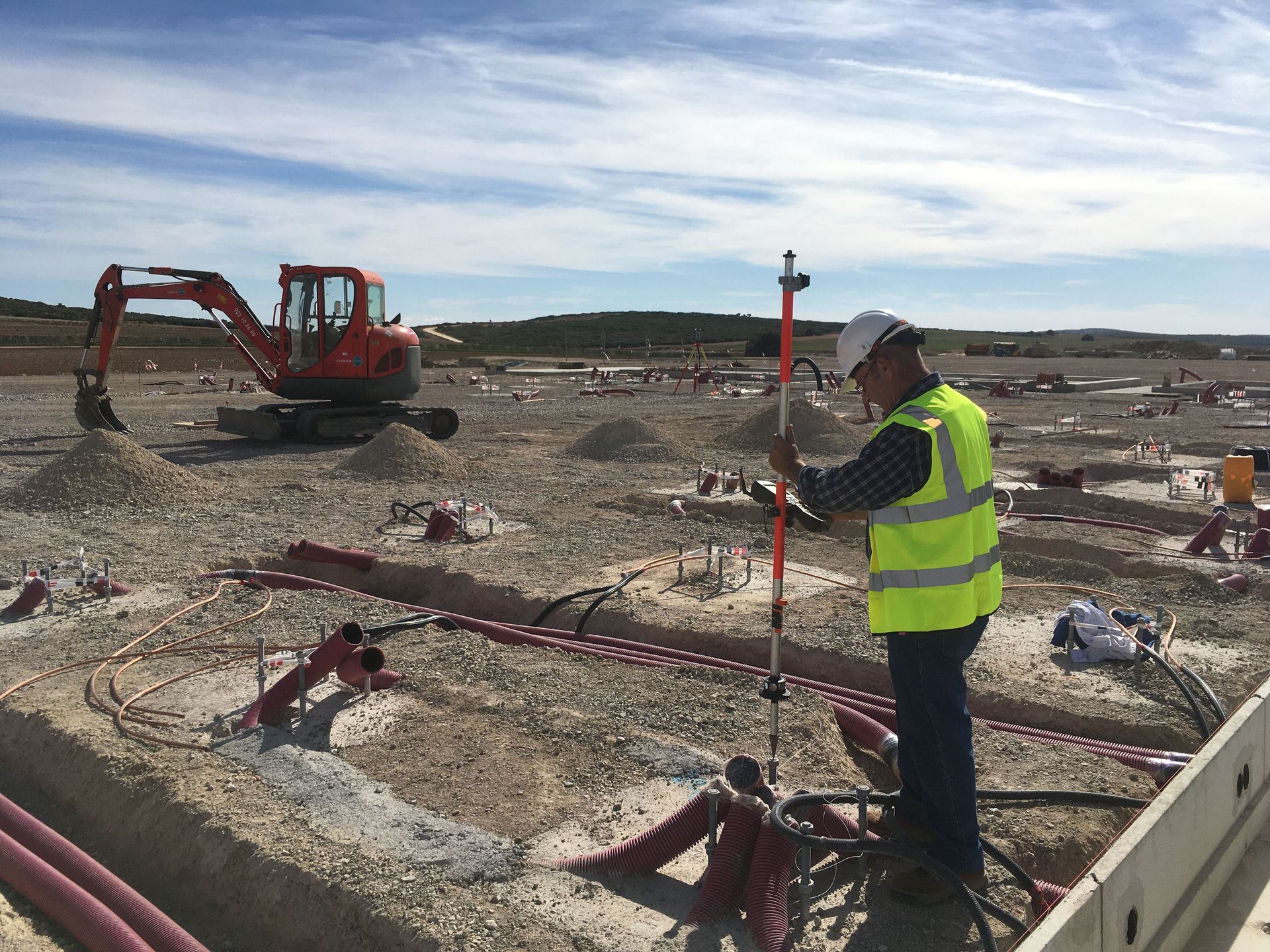 Obreros de la construcción con chalecos de seguridad y cascos. Dentro de un edificio, algunos revisando planos.