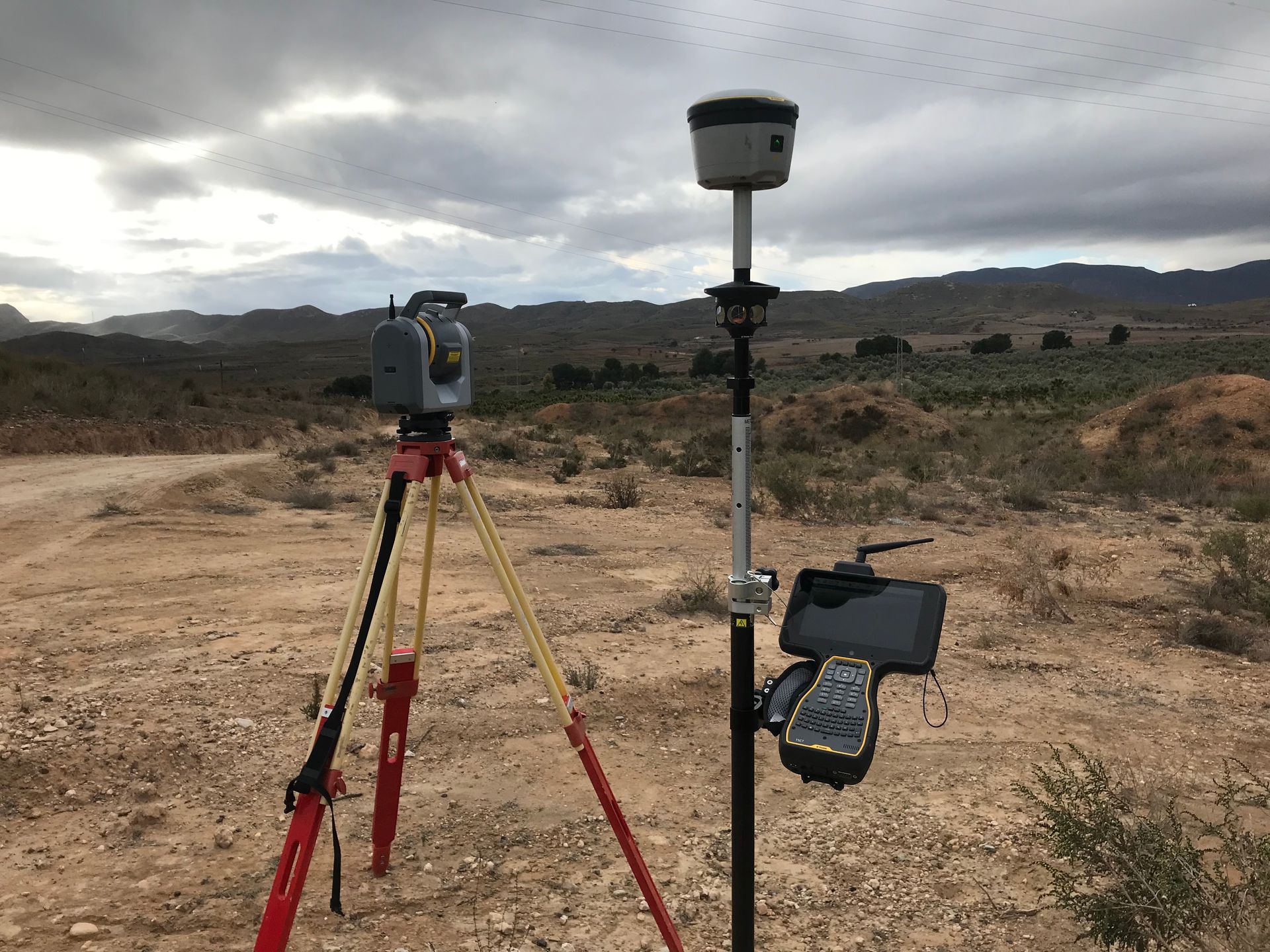 Un instrumento de topografía sobre un trípode, inspeccionando un sitio de construcción con pilares de metal.
