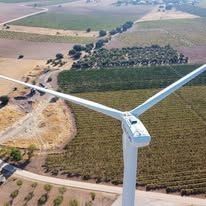 Aerogenerador en un campo, generando energía limpia. Paisaje agrícola al fondo.