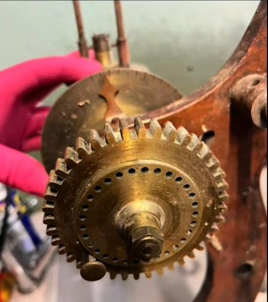 Gros plan sur un mécanisme d'engrenage, tenu par une main gantée, dans un atelier.