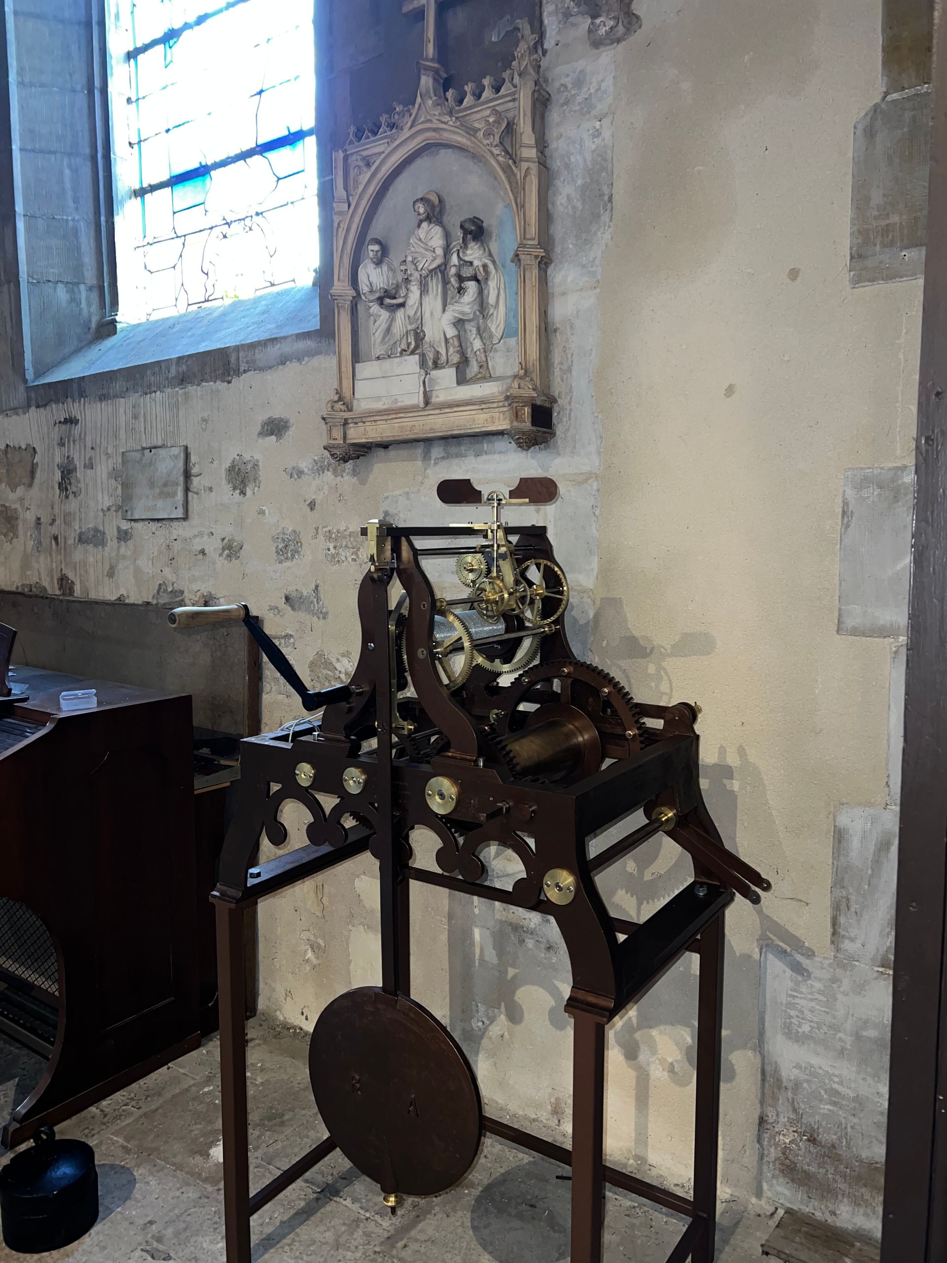 Horologe d'édifice restauré, à côté d'un autel mural et d'une fenêtre.