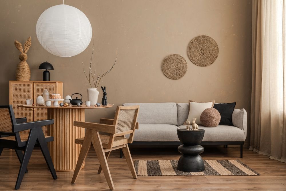 Sala de estar con paredes beige, sofá, sillas de madera y elementos decorativos.