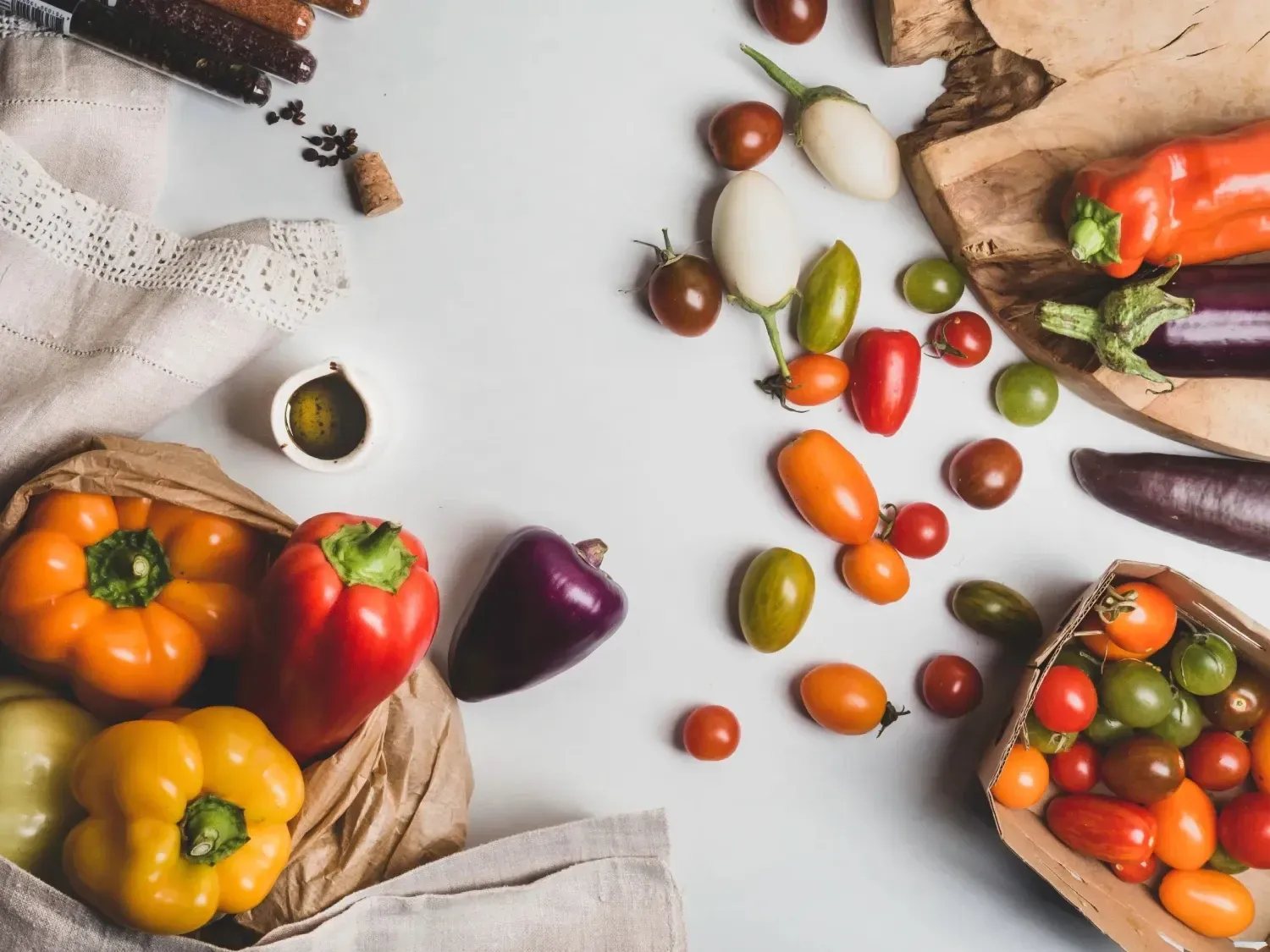 Una mesa cubierta con una variedad de verduras, incluidos pimientos, tomates y berenjenas.
