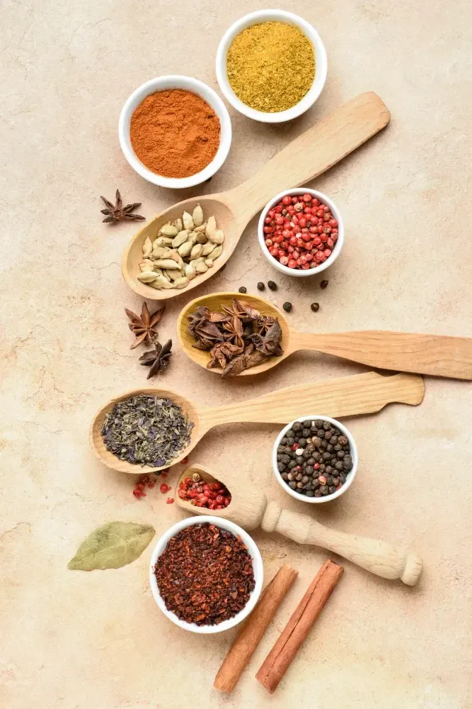 Una variedad de especias en cucharas y cuencos de madera sobre una mesa.