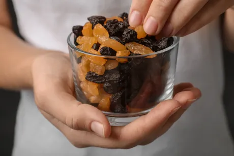 Una persona sostiene un recipiente de vidrio con fruta seca.