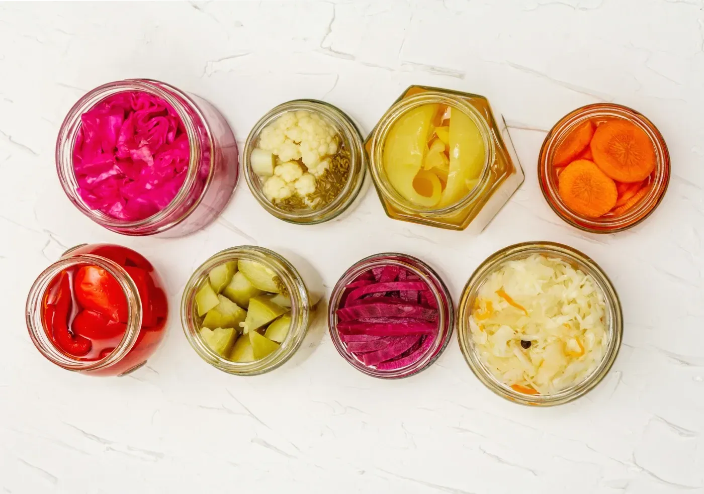 Una variedad de verduras encurtidas en frascos sobre una mesa.