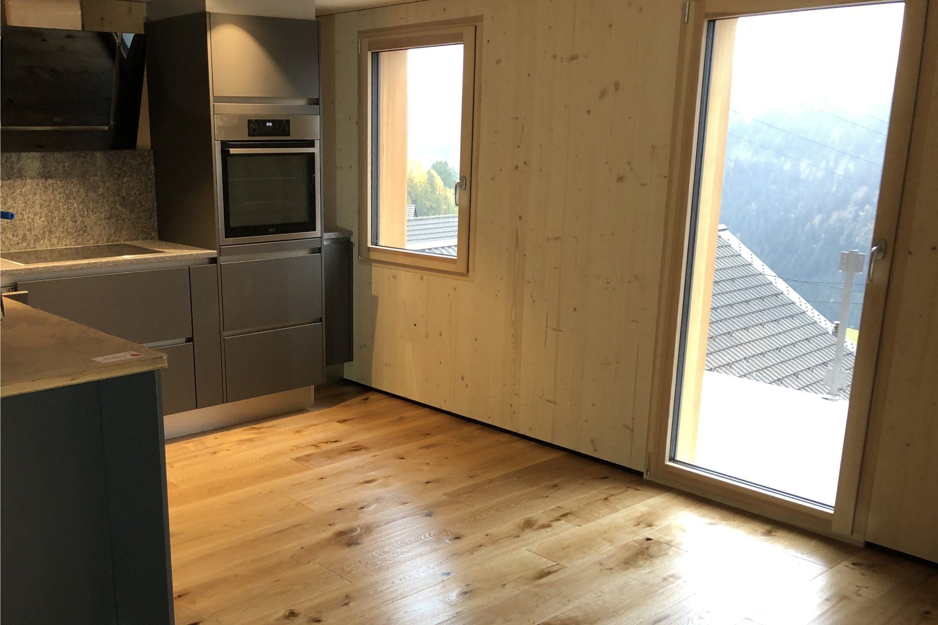 Una cucina vuota con pavimenti in legno e una grande finestra.