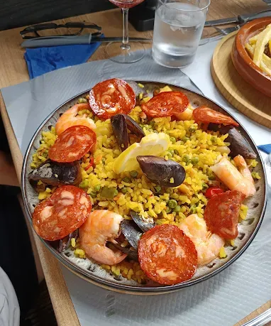 Plat de paella avec chorizo, crevettes, moules et citron.