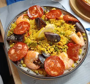 Paella au chorizo, crevettes, moules et citron dans une assiette.