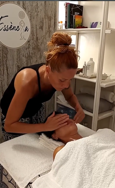 Dona fent massatge facial a una altra dona en un spa.