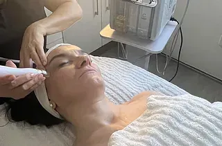 Una mujer está acostada en una cama recibiendo un tratamiento facial.
