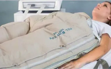 Una mujer está acostada en una cama con una manta sobre su estómago.