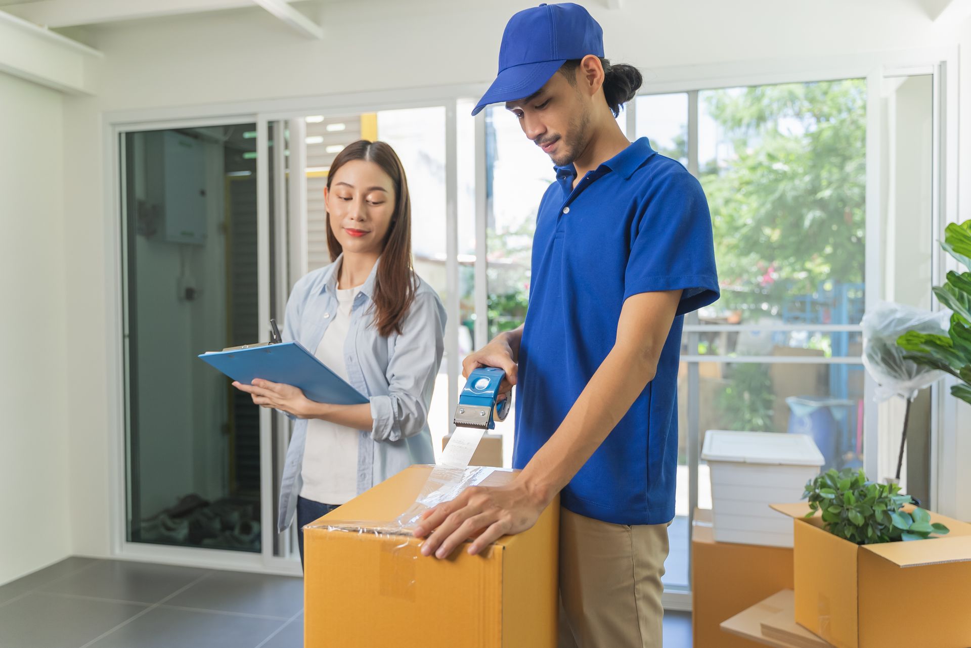 Zoom sur un déménageur fermant un carton avec une scotcheuse