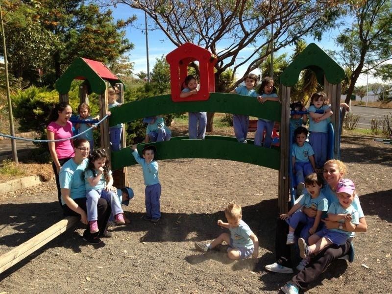 Un grupo de niños posa para una foto frente a un patio de juegos.