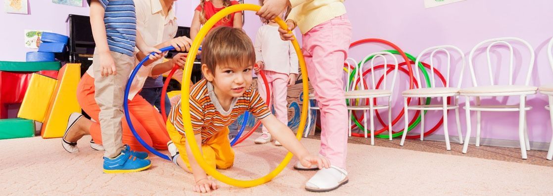 Un grupo de niños está jugando con aros de hula hula en un aula.