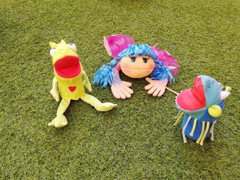 Tres animales de peluche están sentados en la parte superior de un exuberante campo verde.