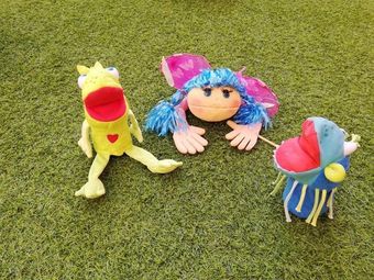 Tres animales de peluche están sentados en la parte superior de un exuberante campo verde.