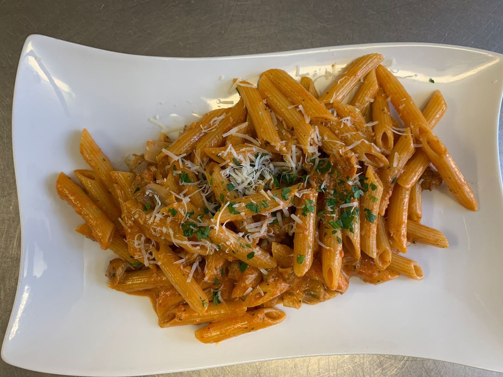 Penne-Nudeln in Tomatensosse, garniert mit geriebenem Käse und Kräutern.