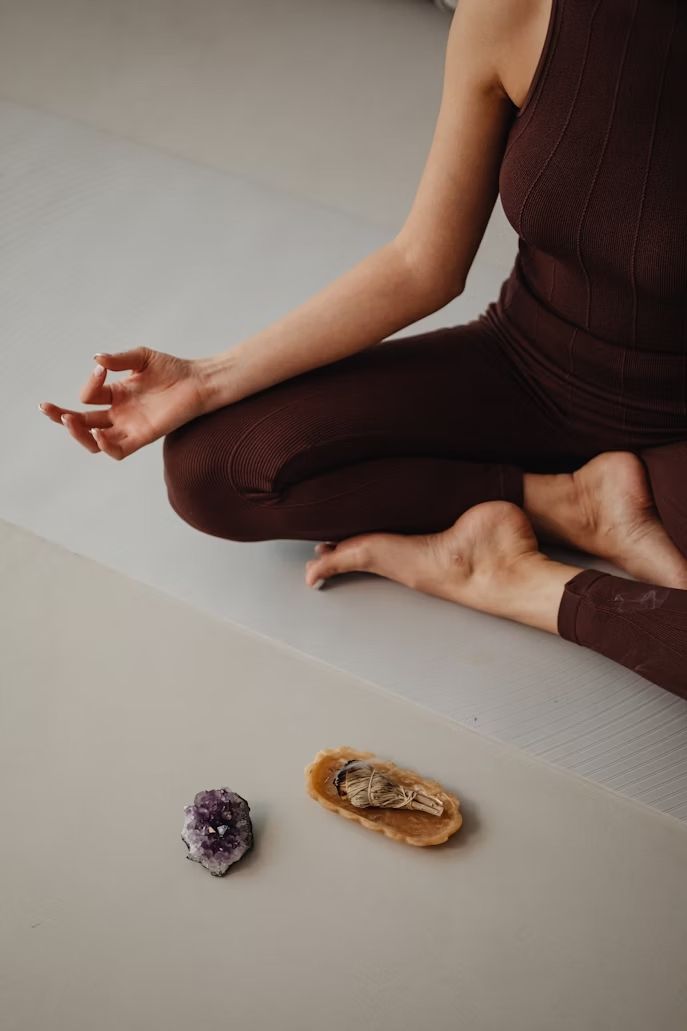 Palo santo humeante, vela encendida, cristales y un cuenco decorativo sobre una superficie texturizada.