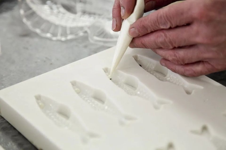 Une personne verse du glaçage dans un moule en silicone.