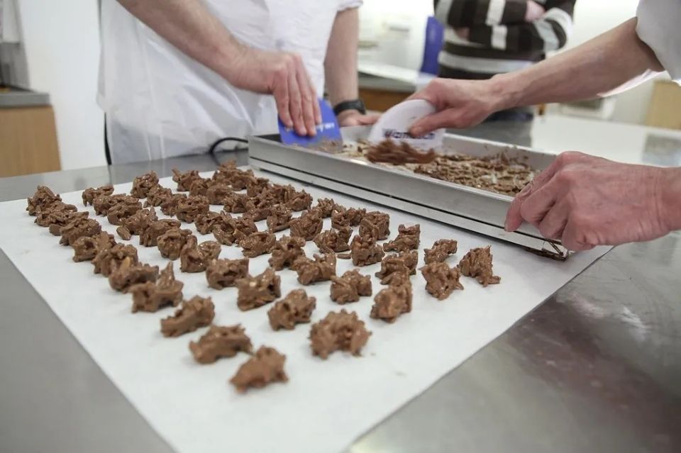 Deux personnes travaillent sur un plateau de nourriture sur une table.