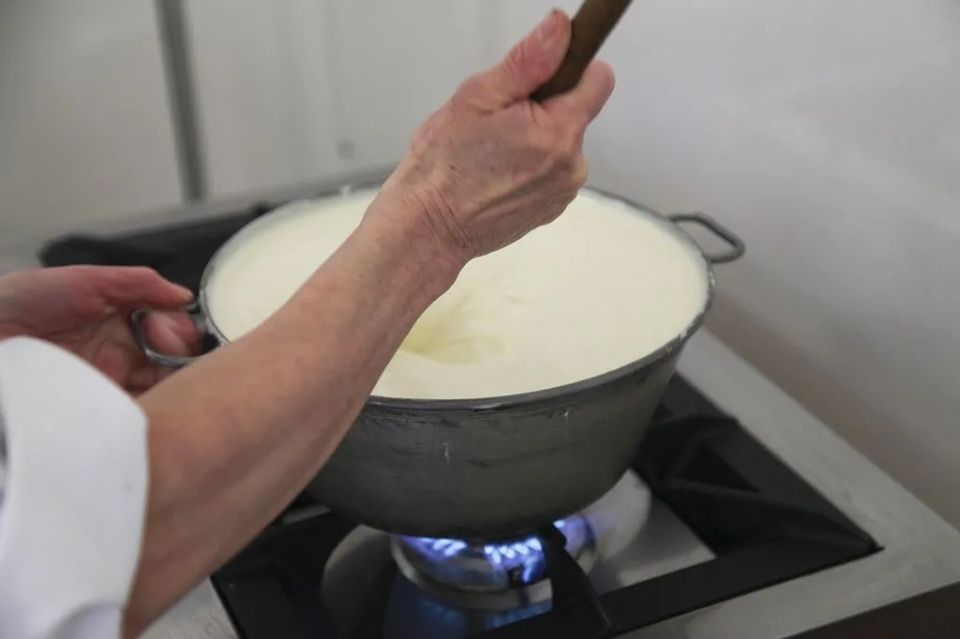 Une personne remue une marmite de soupe sur une cuisinière.