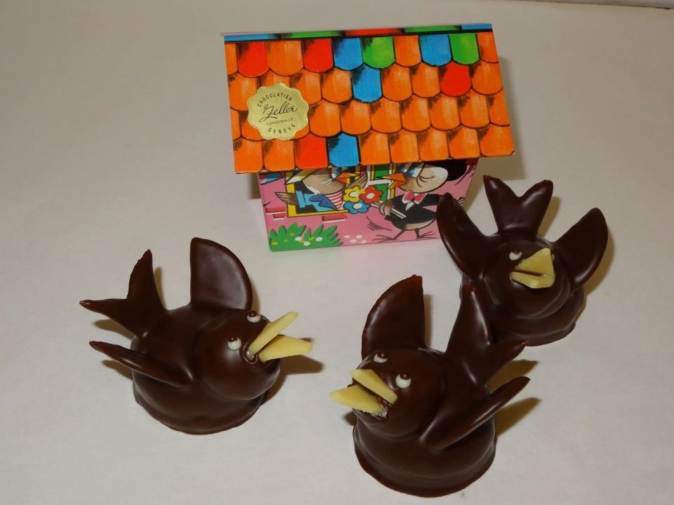 Trois oiseaux en chocolat sont assis à côté d'une boîte colorée