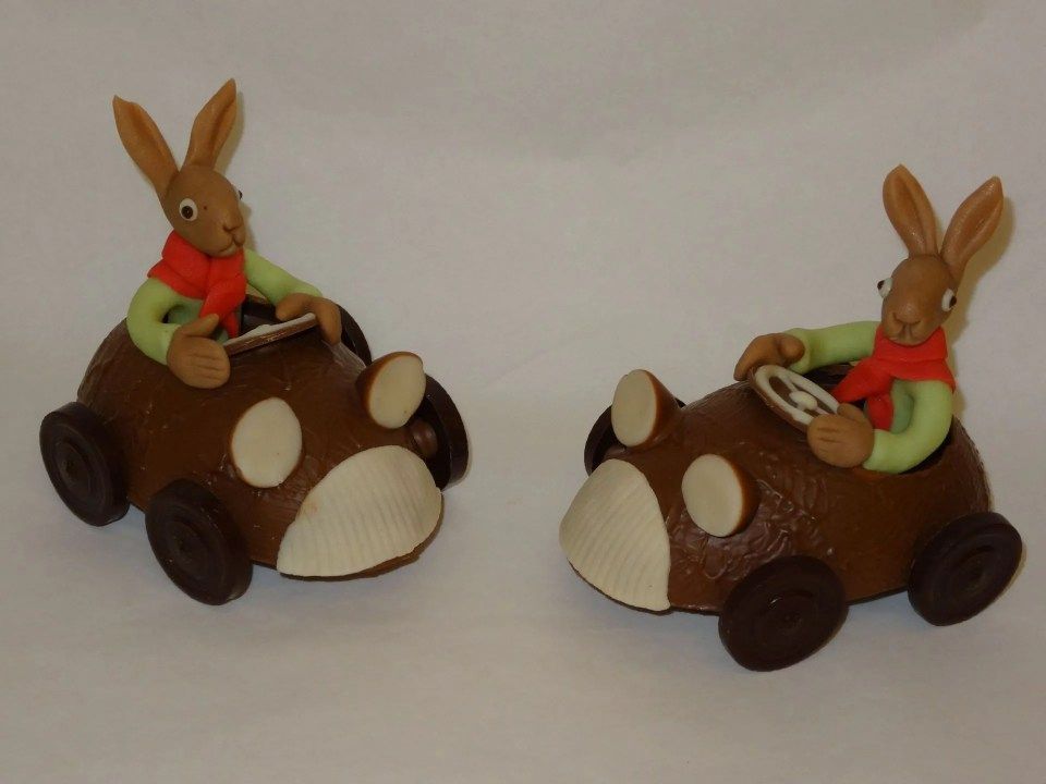 Deux lapins en chocolat conduisent une voiture sur une surface blanche
