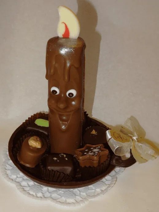 Une bougie en chocolat avec un visage est sur une assiette de chocolats