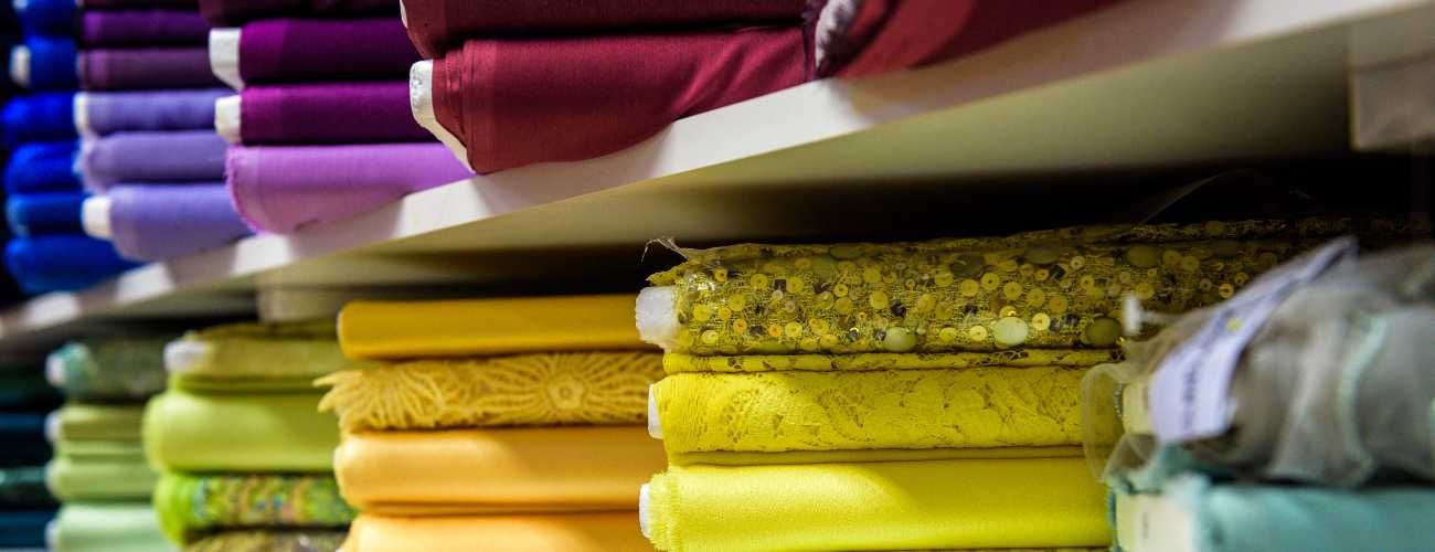 Un estante lleno de rollos de tela de diferentes colores.