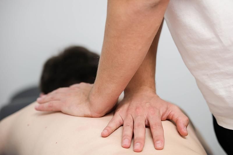 Eine Person massiert einem Mann den Rücken.