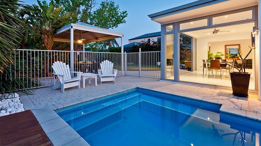 Una gran piscina está en el patio trasero de una casa.