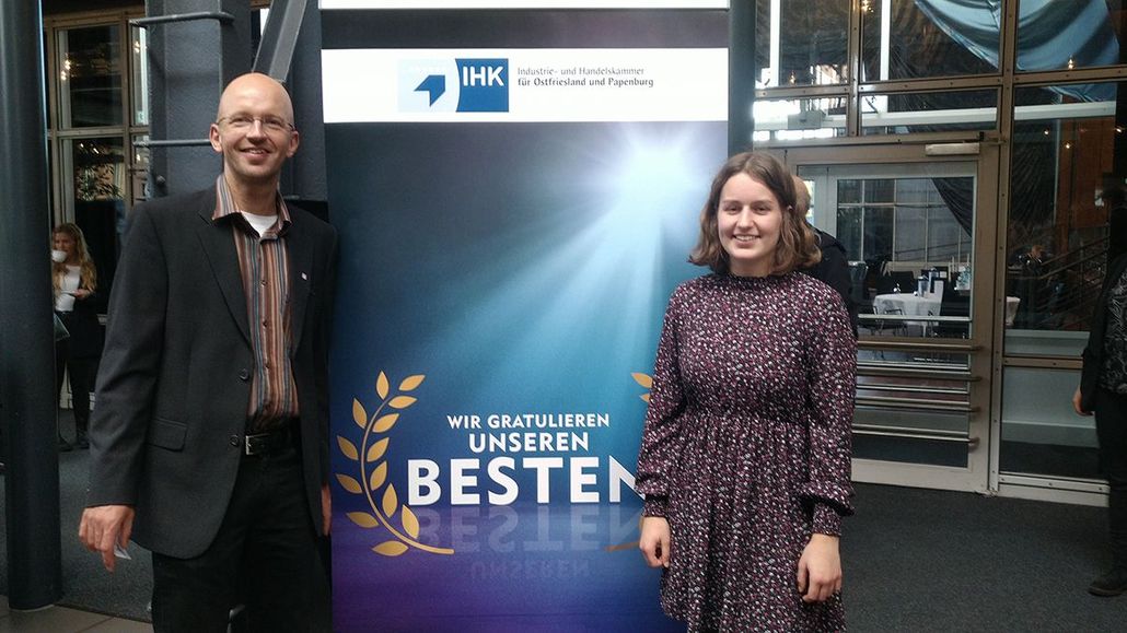 ein Mann und eine Frau stehen vor einem Plakat mit der Aufschrift wir gratulieren unseren Besten