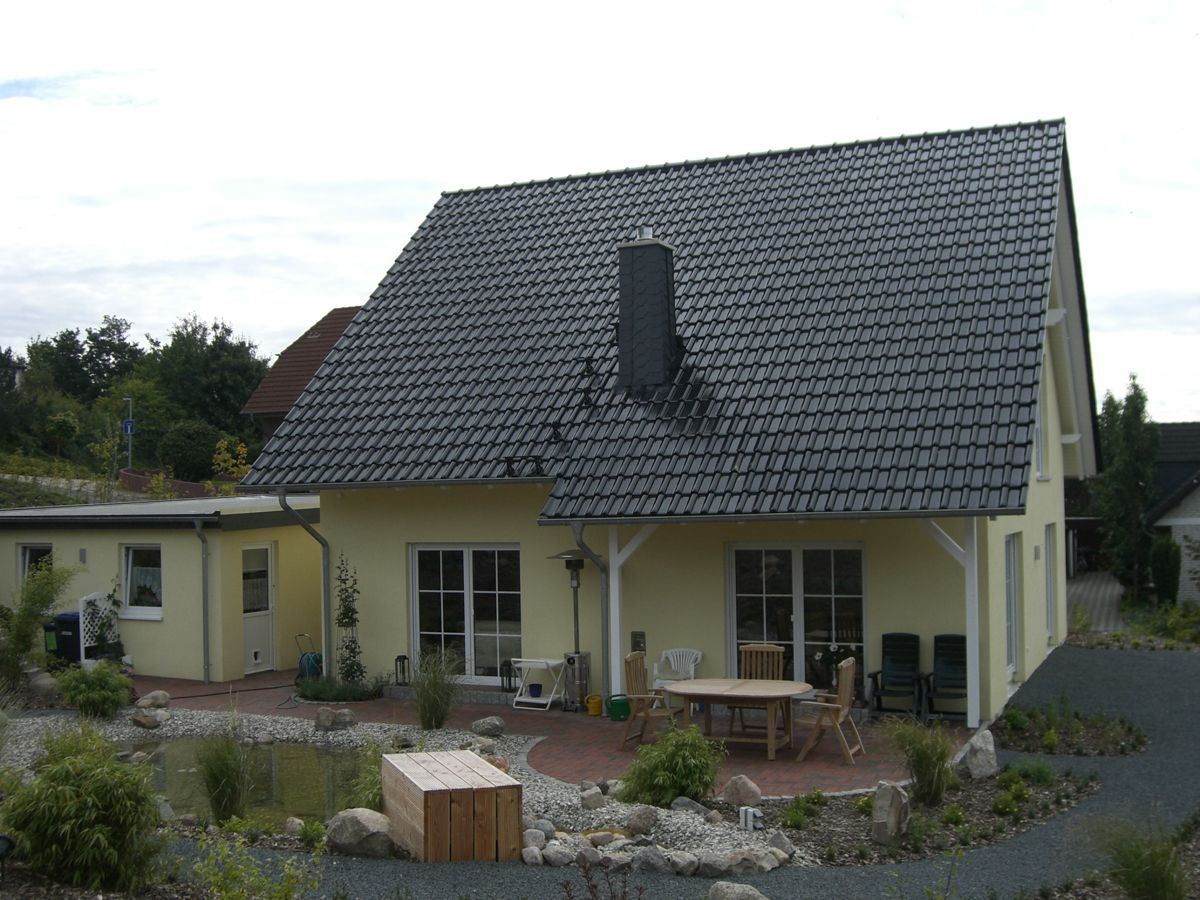 ein Haus mit einem schwarzen Dach und einem Tisch und Stühlen davor