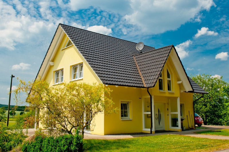 ein gelbes Haus mit einem schwarzen Dach