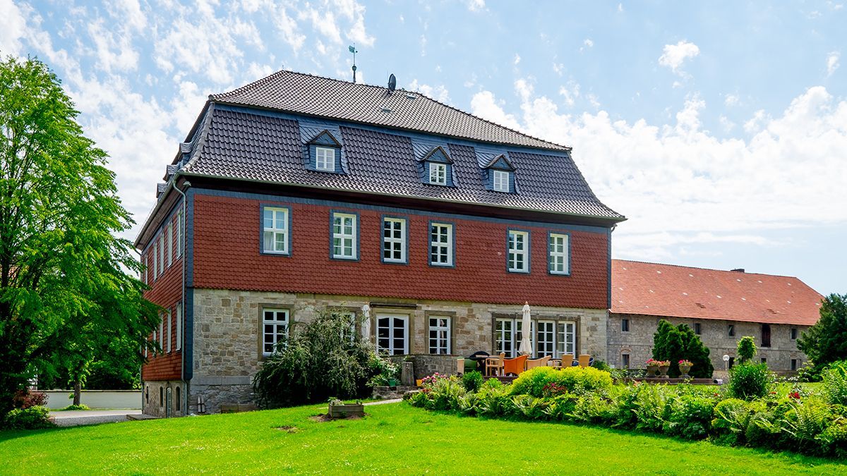ein großes rotes Haus mit einem schwarzen Dach und vielen Fenstern