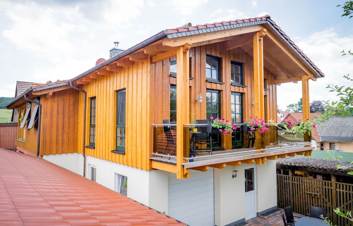 ein Holzhaus mit einem Balkon und einer Garage