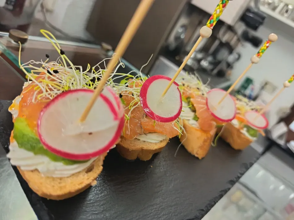 Aperitivos coloridos en porciones pequeñas, coronados con guarniciones circulares sobre una bandeja de servir