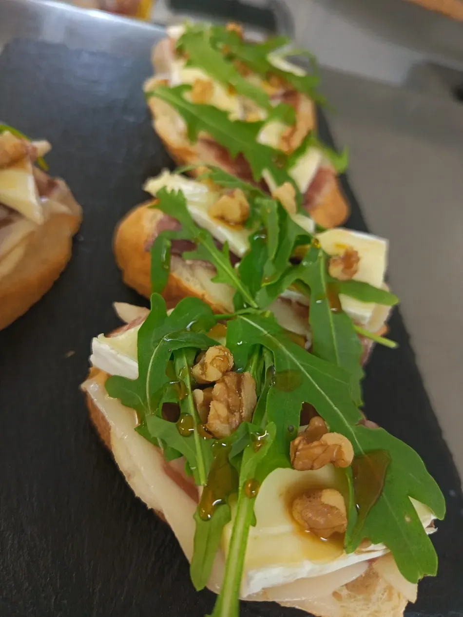 Bruschetta con rúcula, nueces y queso sobre una tabla negra para servir
