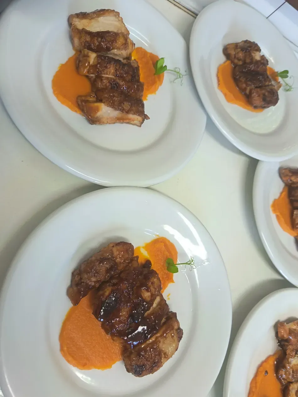 Carne asada emplatada con salsa de naranja en platos blancos dispuestos sobre una mesa
