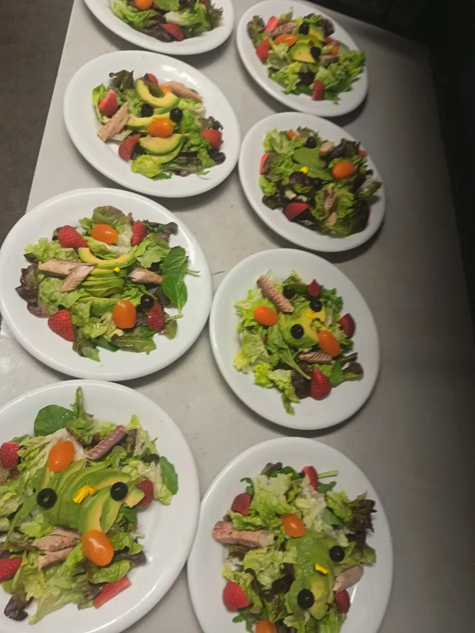 Platos de ensaladas coloridas con lechuga, tomates, pepinos y aceitunas dispuestos sobre una mesa.