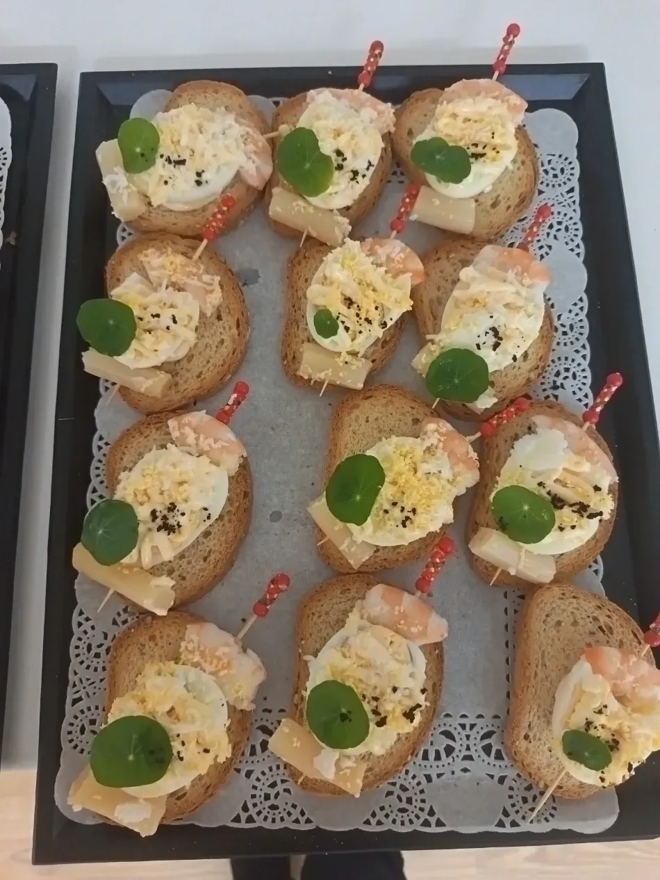 Bandeja de canapés en miniatura con ensalada cremosa y guarnición verde, sobre una fuente cubierta con un mantelito de encaje