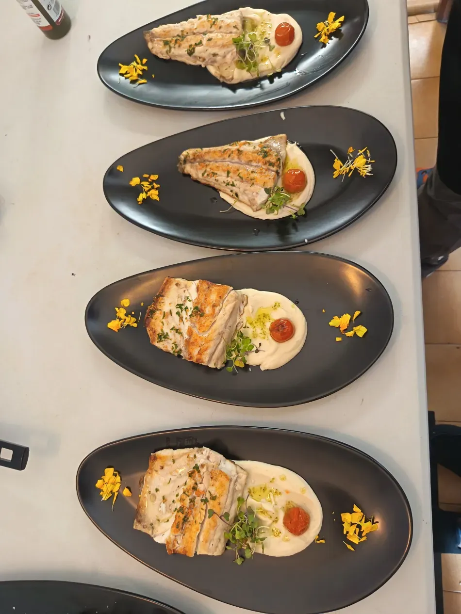 Cuatro platos de salmón con arroz y guarnición, servidos en platos ovalados negros sobre una mesa.