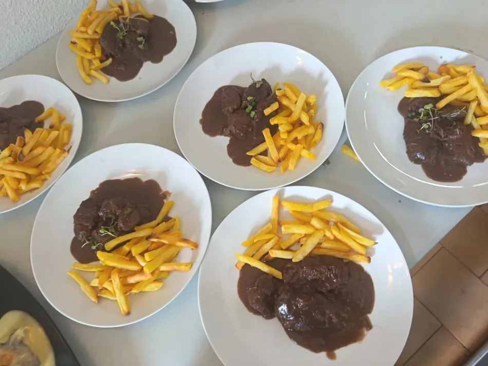 Seis platos de bistec con patatas fritas dispuestos sobre un suelo de baldosas.