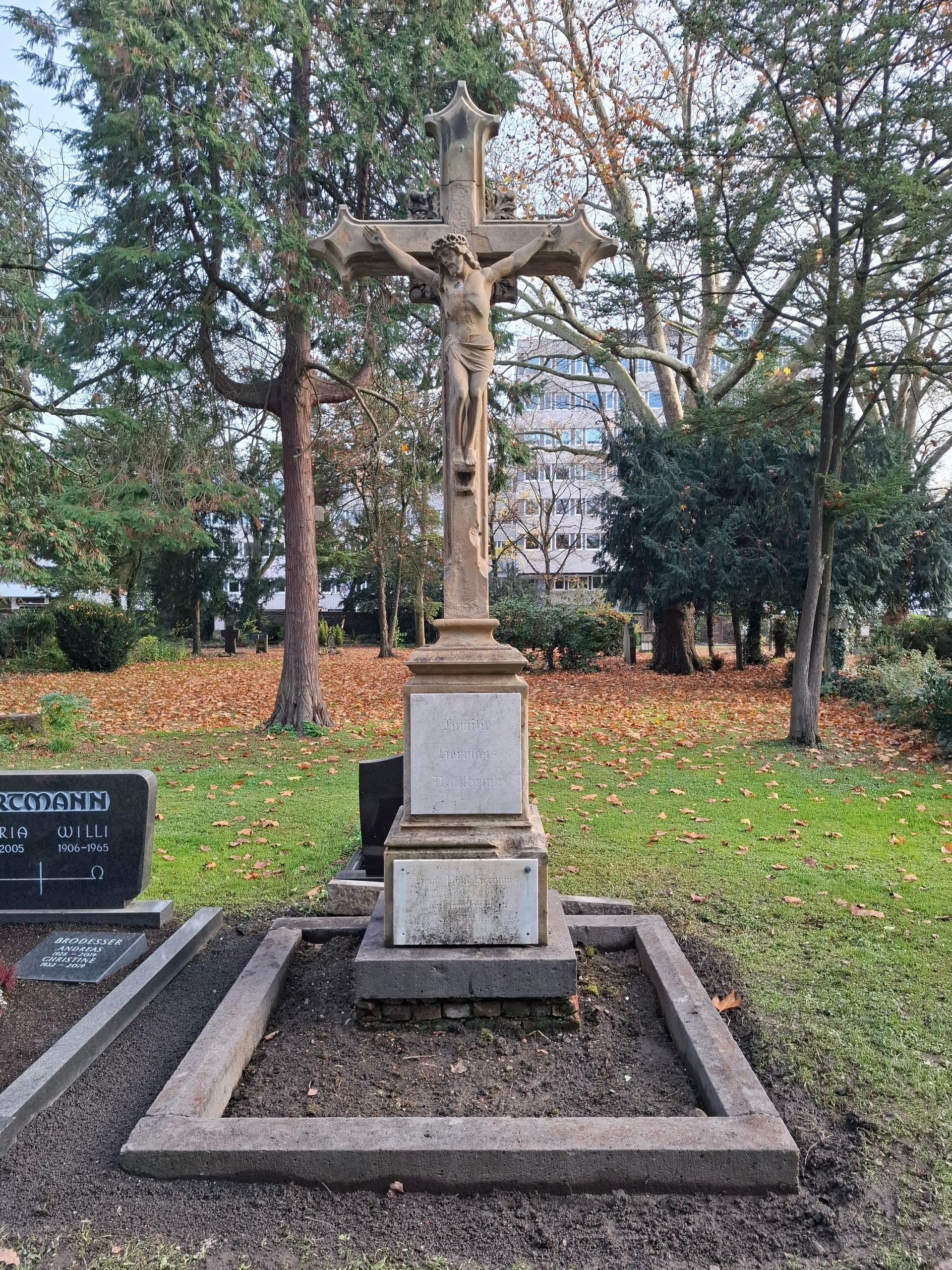Steinkreuz auf einem Grab mit einer eingemeißelten Jesusfigur; Friedhofsszene.