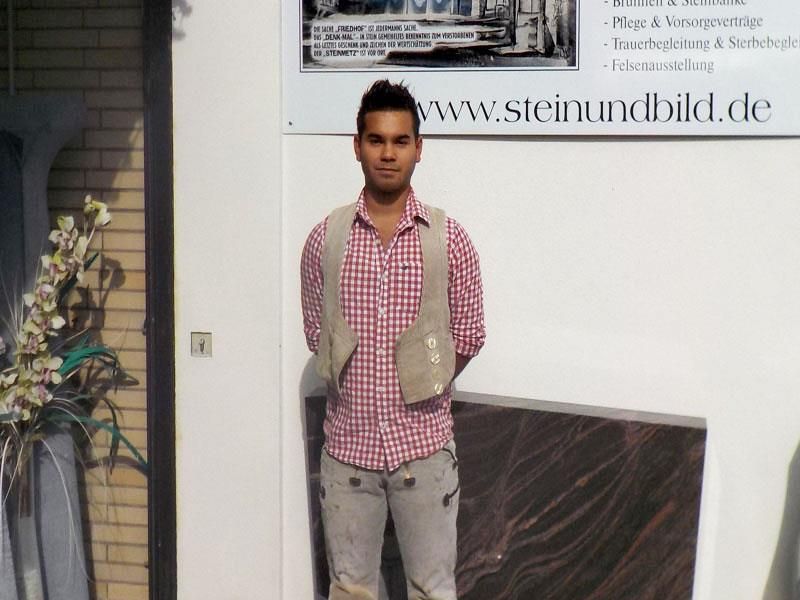 Ein Mann steht vor einem Schild mit der Aufschrift www.steinundbild.de