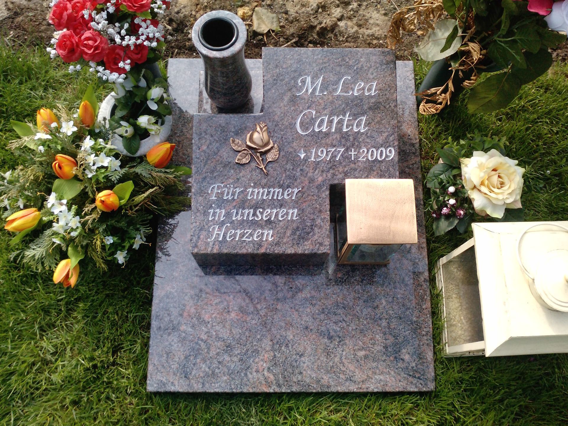 Gravestone with flowers, reads 
