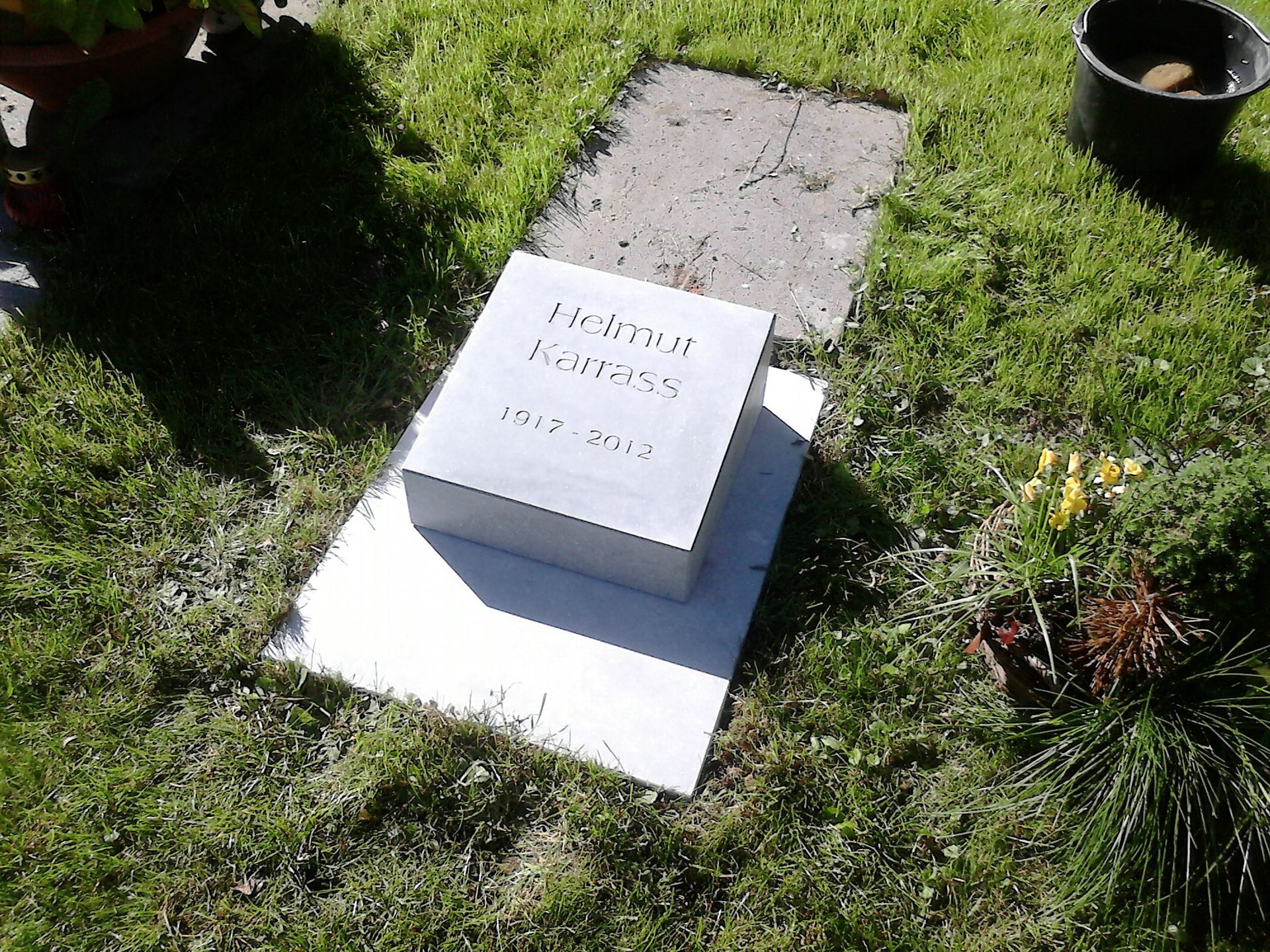 Ein Grabstein auf Gras; der eingravierte Name lautet „Helga Hansen“ mit Geburts- und Sterbejahr.