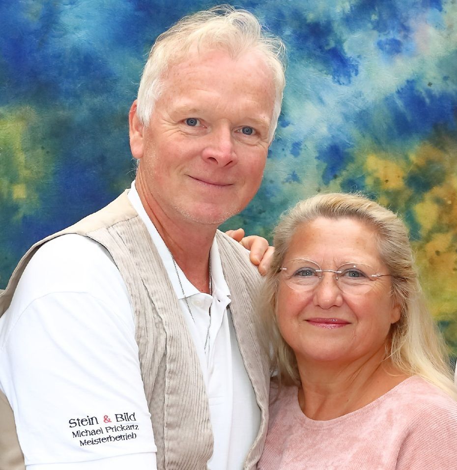 Ein Mann und eine Frau posieren für ein Foto vor einem Schild mit der Aufschrift „Stein & Bild“